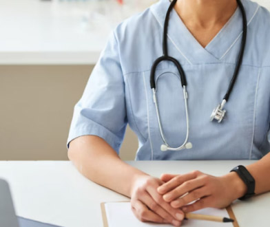 Osoba sjedi za stolom u medicinskoj uniformi